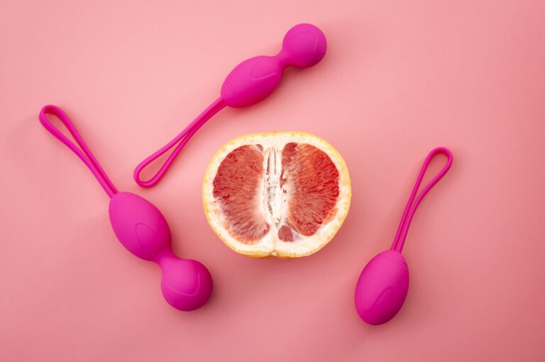 Metaphor for pelvic floor exercises, gynecology and treat urinary incontinence through strength exercise concept with kegel weights and half a grapefruit isolated on pink background